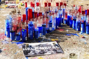 candles on the street with a sing that says "Help Nepal"