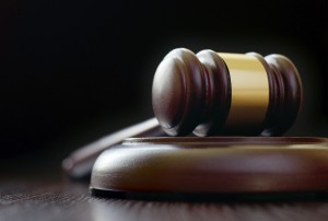 Low-angle close-up of a vintage classical gavel placed on a round sound block, on a wooden table, with copy space on black background