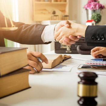 Defense base act lawyers shaking hands with client.